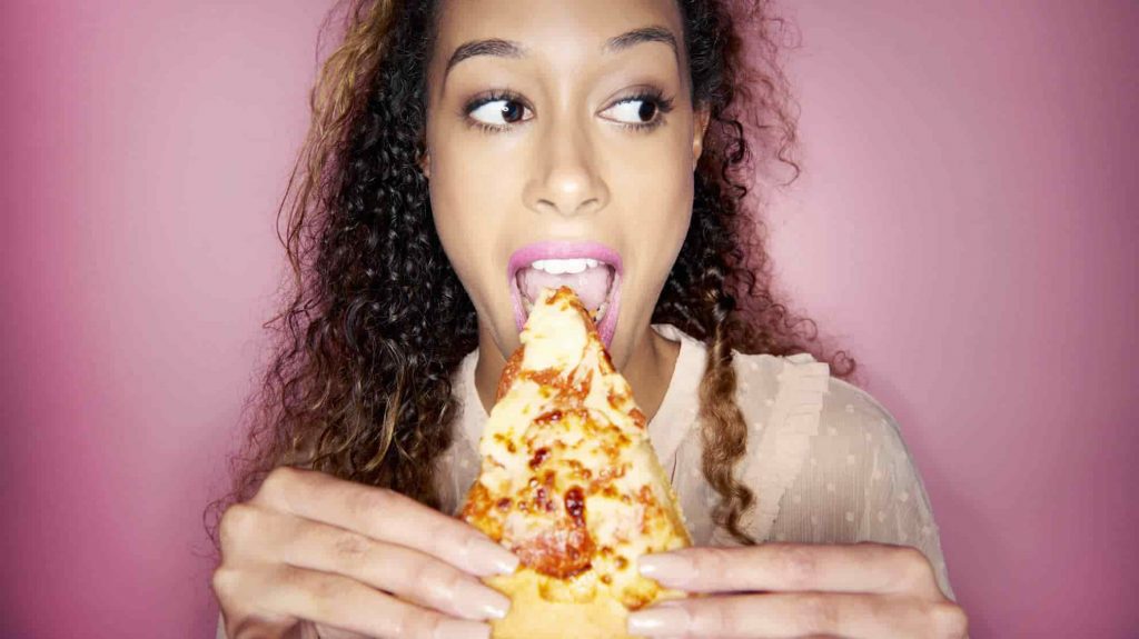 chica comiendo una rebanada de pizza